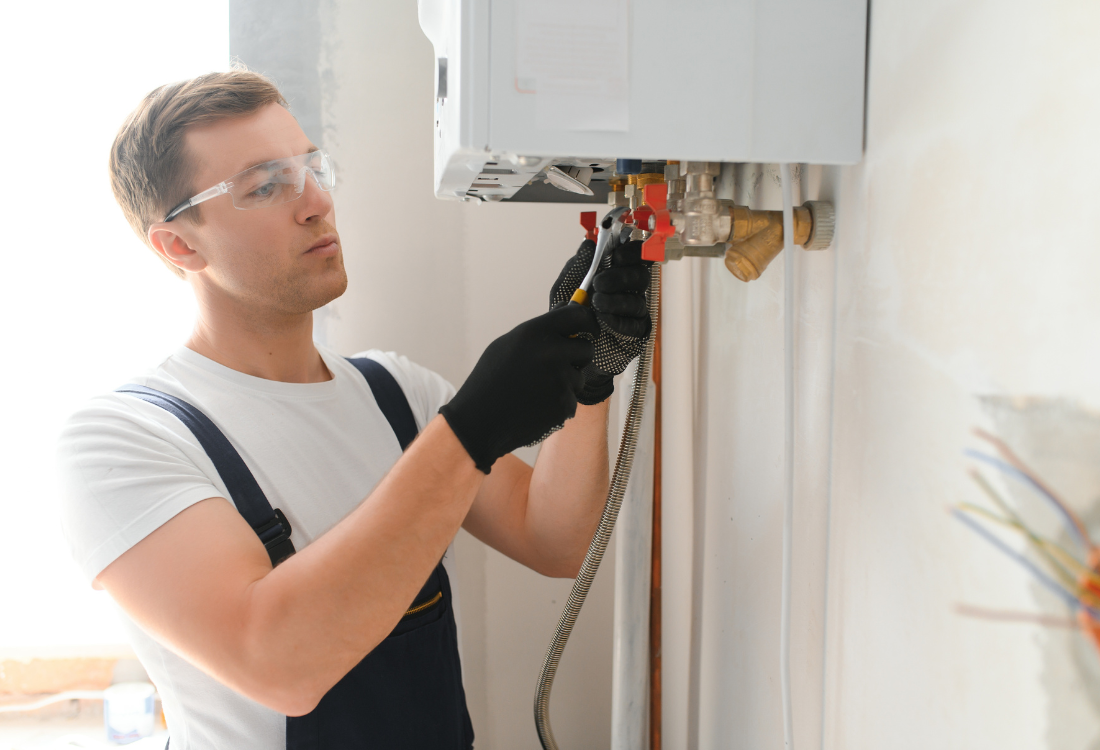 A heating engineer preparing a main boiler for winter by conducting maintenance on the boiler.