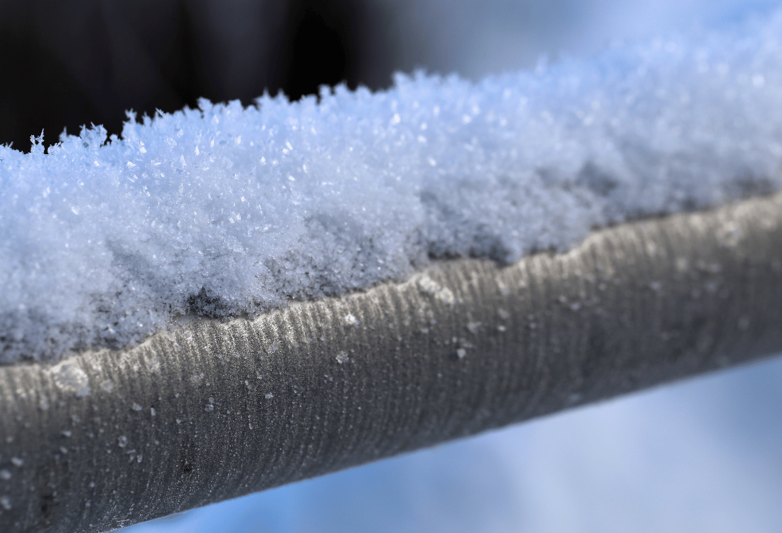 An external boiler condensate pipe covered in a thick layer of snow and ice.